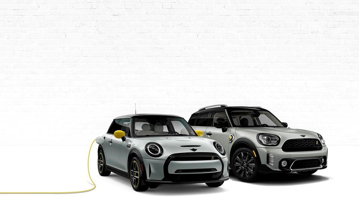 Two MINI Electric vehicles with one on left being charged.