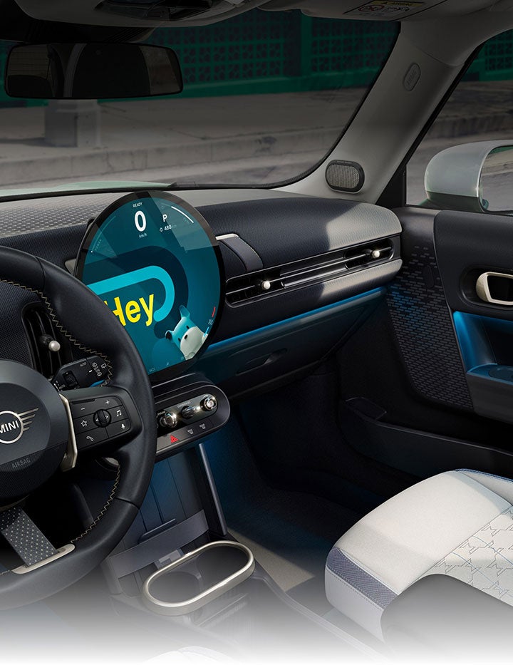 An angled-view of the inside of the Mini Cooper Hardtop 2 Door taken from the passenger's side showcasing the front Sports Seats with blue skies and trees out the windows.