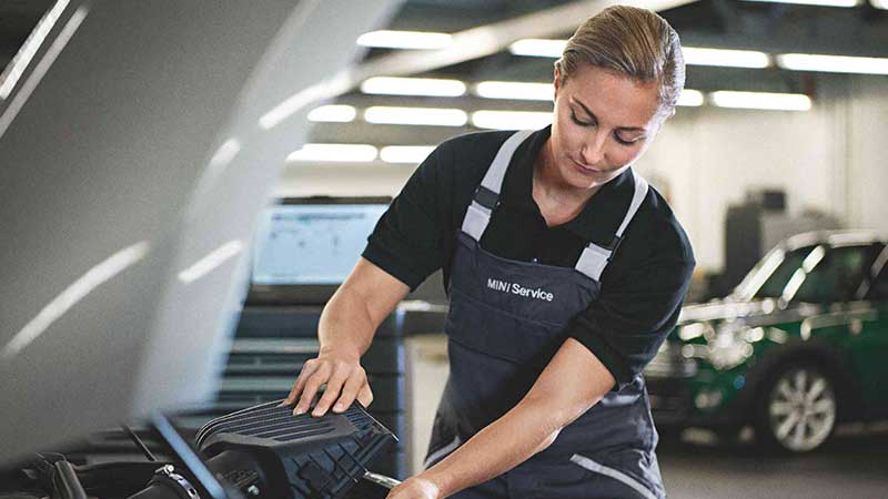 A MINI technician inspecting a vehicle.