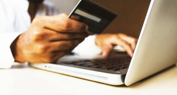 Hand holding credit card in front of open compute | MINI of Rochester in Rochester NY