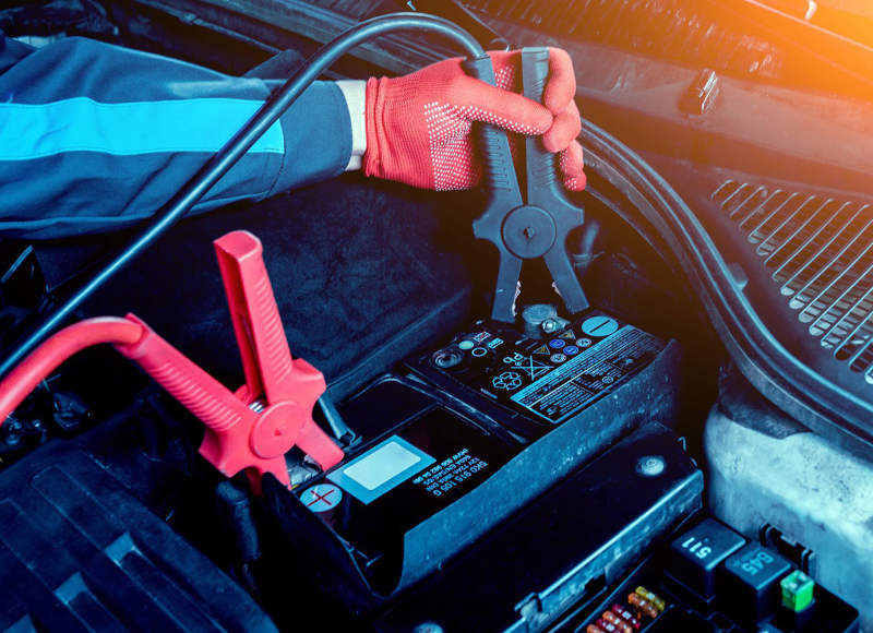 Technician inspecting a car battery under the hood