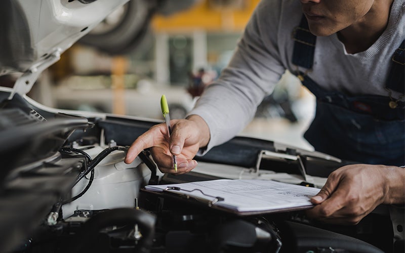 Technician inspecting a car battery under the hood