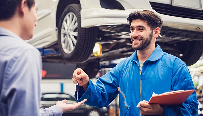Technician handing over car keys to a customer at a service center